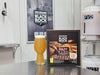 New Zealand Black Rock Hazy IPA beer bottle and box on a bar counter with a blurred background.