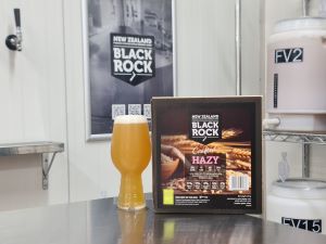 New Zealand Black Rock Hazy IPA beer bottle and box on a bar counter with a blurred background.