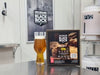 Beer bottle with a label and a box of Black Rock IPA Brew in a Bag kit on counter, with a 'Black Rock' poster in the background.
