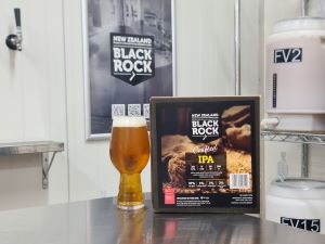 Beer bottle with a label and a box of Black Rock IPA Brew in a Bag kit on counter, with a 'Black Rock' poster in the background.